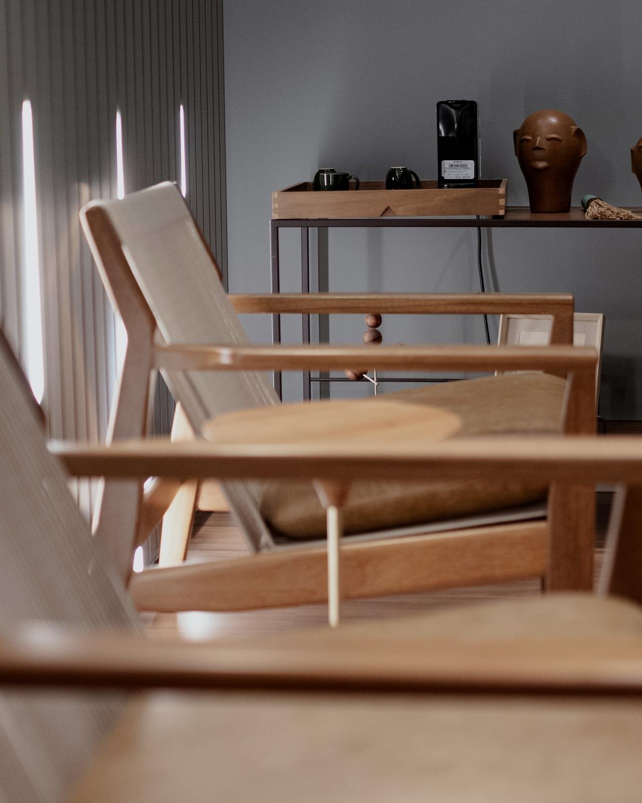 Sala de reunião do escritório, com mesa de vidro escuro, cadeiras de couro caramelo e armário de madeira iluminado.